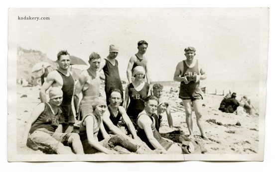 Vintage snapshot of 1920s group at the beach, including camera